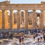Tourists visit the Parthenon on the Acropolis in Athens under a clear blue sky