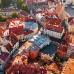 Aerial view of Tallinn Old Town, showing red-tiled rooftops, historic buildings and a church tower