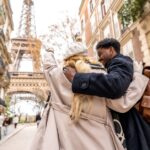 Couple embrace on a Paris street with the Eiffel Tower behind them, enjoying a sightseeing trip