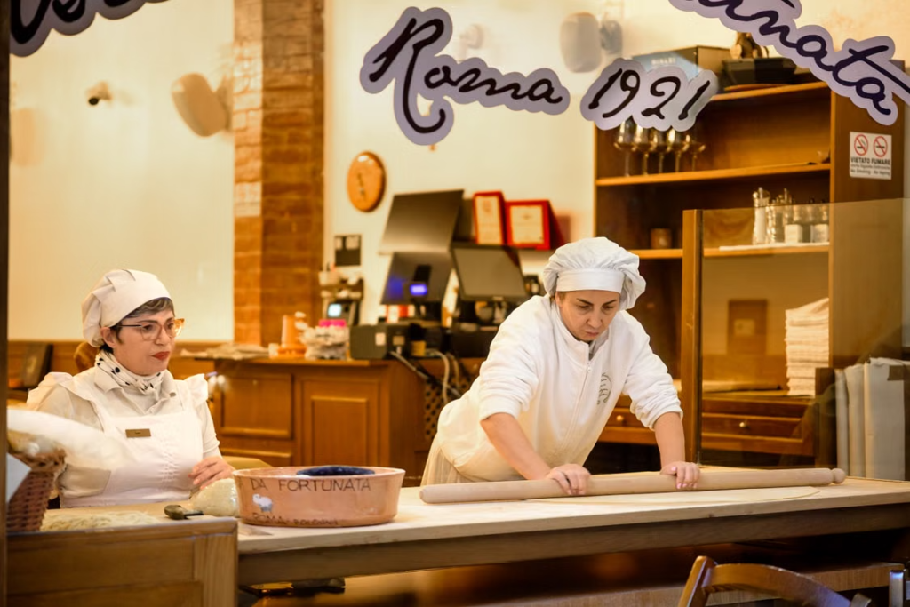 Pizza makers prepare fresh dough behind a counter in a traditional Italian pizzeria