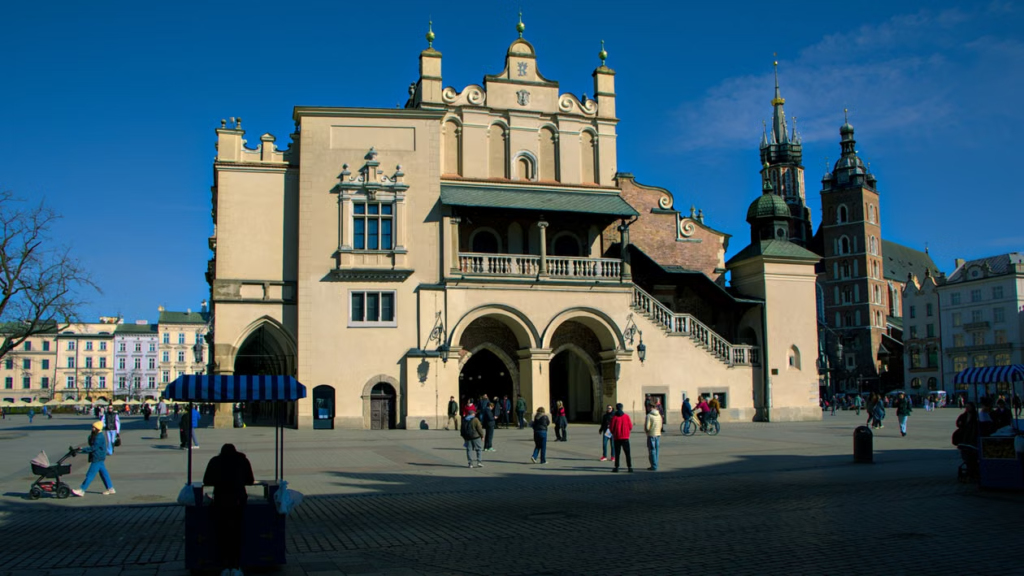 Cloth Hall stands in Kraków's Main Market Square with visitors walking across the open plaza