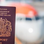 British passport held in front of a blurred passenger aircraft at an airport