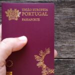 Hand holding a Portuguese passport over a dark wooden surface