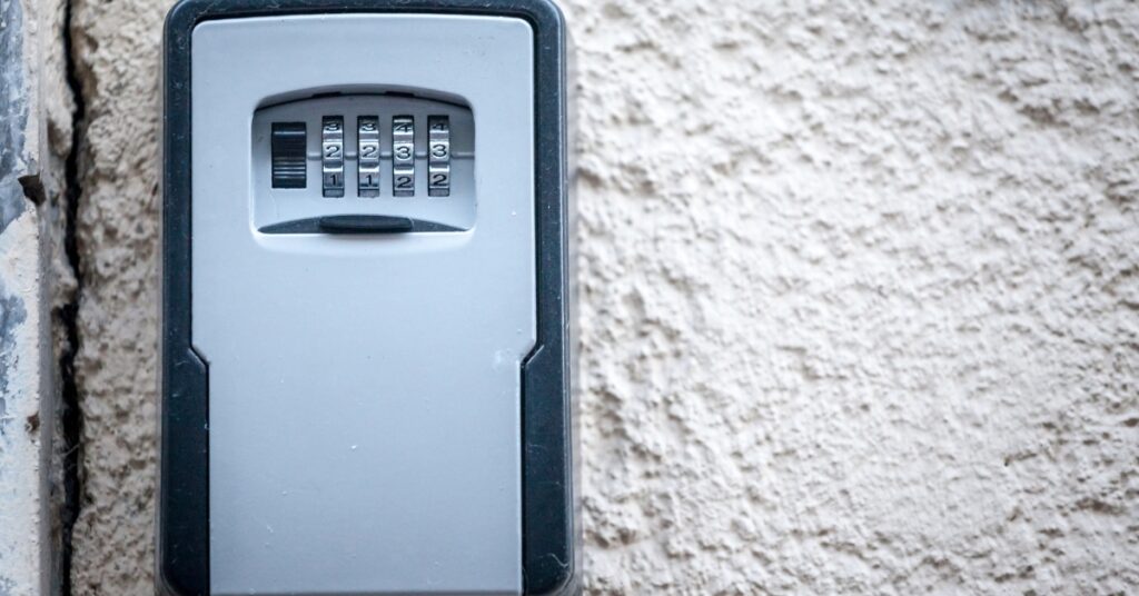Wall-mounted key safe with a four-digit combination lock on a textured exterior wall
