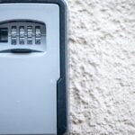 Wall-mounted key safe with a four-digit combination lock on a textured exterior wall
