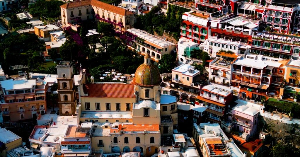 Aerial view of a domed church surrounded by colourful hillside buildings in Positano, Italy